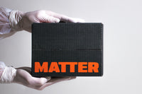 A person in gloves holds a black subscription box labeled MATTER, featuring real science artifacts for curious minds