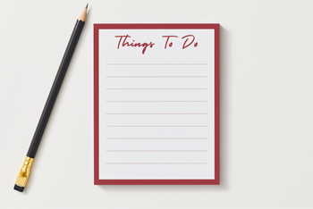 Things To Do notepad with a deep red border and lined pages, shown next to a black pencil on a soft gray desk