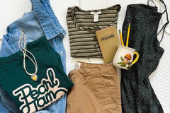 A grunge flat lay outfit consisting of a band t-shirt, necklace, khaki pants, a vintage dress and striped top. 