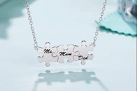 Silver puzzle necklace 3 piece pendants with each pendant inscribed with either “Mom, Dad or Me” each puzzle piece is held
Together  as one 