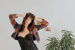 a model wearing modern secondhand corset, vintage nineties jacket with a bold pattern and pleated pants