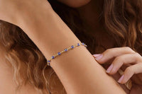 Model wearing the 14K gold plated evil eye bracelet on her wrist, showing blue evil eye charms on a delicate adjustable gold-tone chain.