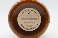 Bottom of a 16oz Burlap Bag amber jar with the kraft safety sticker: 100% natural US soy, hand poured in Austin, 13oz wax
