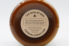Bottom of a 16oz Burlap Bag amber jar with the kraft safety sticker: 100% natural US soy, hand poured in Austin, 13oz wax