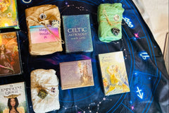 tarot and Oracle decks wrapped in tissue and brown paper surrounded by unwrapped tarot and oracle decks and crystals 