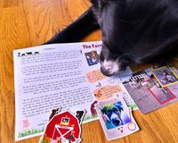 Black and white dog Banjo is showing off a letter he wrote with a farm sticker, a sticker of him and a postcard