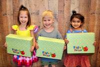 Three cheerful smiling children proudly holds a Wiggle Worms Kit, eager for hands-on crafting fun...