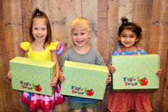 Three cheerful smiling children proudly holds a Wiggle Worms Kit, eager for hands-on crafting fun...
