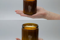 Size comparison in an open hand: a 9oz Burlap Bag amber candle jar above the larger 16oz double-wick jar