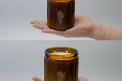 Size comparison in an open hand: a 9oz Burlap Bag amber candle jar above the larger 16oz double-wick jar