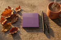 Purple sticky note pad on a wood table beside a pen, a steaming mug, and scattered autumn leaves. Journey Box item.
