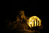 Extremely dark photo (almost pitch black) with scary horror like skull with body, that is holding a yellow ball.