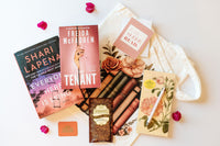 A customizable book subscription box featuring two novels, a tote bag, and bookish items for readers