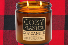 Cozy Flannel 16oz double-wick soy candle by The Burlap Bag, peppercorn and musk scented amber jar on red and black buffalo plaid