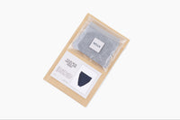 Sample of a packaged pair of gray underwear along with a copy of the notecard that comes with each subscription on top of mailer