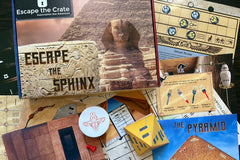 An unboxed picture of "Escape the Sphinx" showing papers, props, and puzzles used when playing the game.