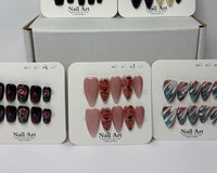 Multiple press-on nail sets arranged on branded display cards labeled nail art, highlighting different color themes and cohesive design coll