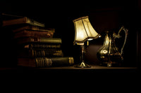 dark image with books lamp and a coffee and the lamp is shining very bright. But at the same time its almost black