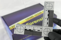A blue box containing a forensikit is displayed in the back while a white evidence scale is in the foreground