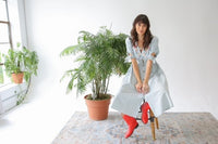 a beautiful cottagecore embroidered vintage dress and red cowboy boots to match on a model in front of a window