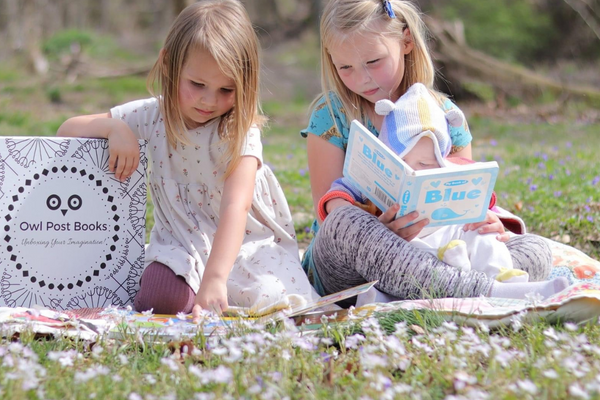 Young child reading beside an Owl Post Books kids subscription box filled with Baby Animals and crafts, a perfect holiday gift for toddlers.
