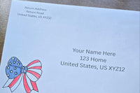 White envelope with printed sample U.S. mailing and return addresses, featuring a red, white and blue patriotic bow with stars and stripes.
