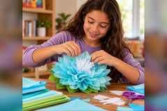 A tween girl seated at a table, putting the finishing touches on a tissue paper flower she is making.