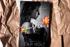 A slender woman holding a shaw against her body. The title Splashed appears in the middle. Flanked by two flowers. 