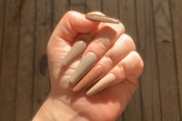 Long, coffin nude set. Each nail is a different solid color ranging from dark brown, medium brown, grey brown, red brown, and cream.