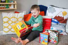 Happy toddler enjoying Owl Post Books kids subscription box with holiday gift books, perfect Christmas present for young readers.