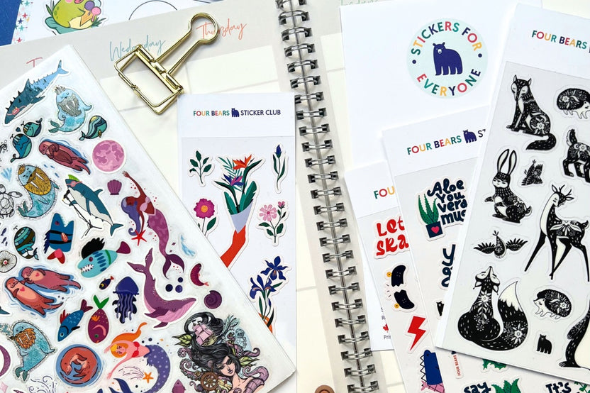 A tidy desk featuring an open monthly planner with colorful decorative sticker sheets displayed beside it, perfect for personalizing and org