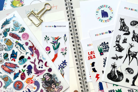 A tidy desk featuring an open monthly planner with colorful decorative sticker sheets displayed beside it, perfect for personalizing and org