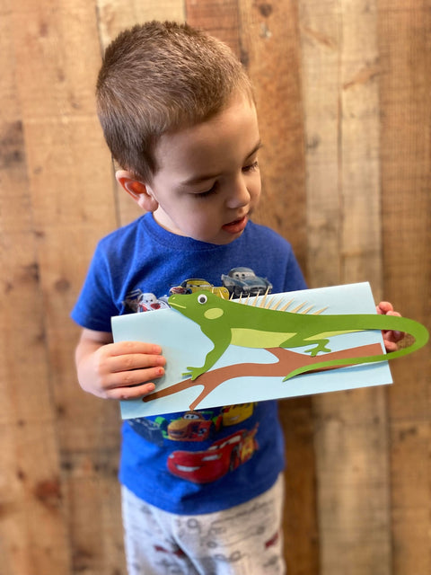 Smiling child holding a colorful Wiggle Worms Kit iguana, ready to explore fun crafts and activities.