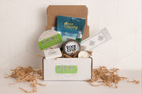 monthly sip + scent subscription box includes one travel-sized candle and one beverage of choice, plus a bookmark and sometimes a sticker.