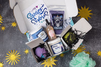 A person holds a teal Bath Bevy monthly subscription box tied with a red ribbon, ideal for self care gifts