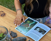 A photo of a mother and daughter reading the paperwork included in the box. There is a finished terrarium on the table aswell.