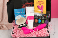 Colorful items including a pink dual-head vibrator and massage oils in the Woman SOLO Adult Subscription Box for self exploration