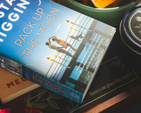Close up of the novel Pack Up the Moon. Introverts Read & Relax box contents - shows a candle on the side of the photo.