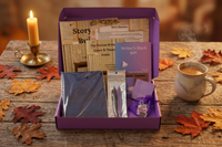 Open Journey Box on a rustic wood table with a candle, coffee, and autumn leaves, revealing the workbooks, journal, pens, and notes inside.