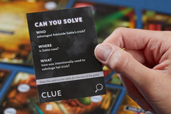 A person holding a black card with this text: can you solve, who, sabotage, clue, what, item was intentionally used.