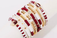 Game Day 8-piece stackable friendship bracelet set in maroon, white, and gold beads displayed wrapped diagonally around a white cylinder sta