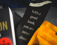 Introverts Read & Relax box contents. Close up of a bookmark that says "With a Good Book You Are Never Alone,"
