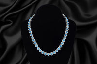 blue sapphire tear drop shaped necklace on a black velvet display showcasing a silk black background giving a luxury vibe