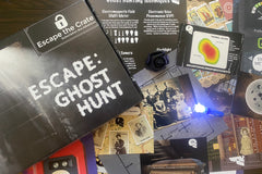 An unboxed picture of "Escape: Ghost Hunt" showing papers, props, and puzzles used when playing the game.