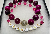 Handmade encouragement bracelet with soft pink stone beads, rose faux crystal accents, and white letter beads spelling “FEARLESS” 