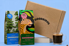Two bags of coffee, a Goodbirds box and a cup of coffee, part of Goodbirds monthly coffee subscription of 2 12oz bags of coffee