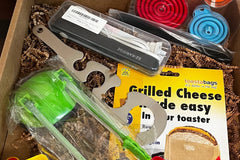 A subscription box full of different kitchen gadgets that are used for cooking, meal prep, or clean up.