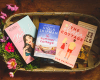 Introverts Read & Relax box contents - four novels from previous boxes in a basket on a wood table. 