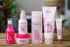 pink products standing on a wooden shelf with a cozy room in the background. All the products are pink.