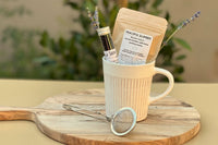 Two Loose Leaf Tea Flavors in ceramic mug with metal infuser on side. Peaceful Slumber and Vanilla Soothe for wellness in every sip. 